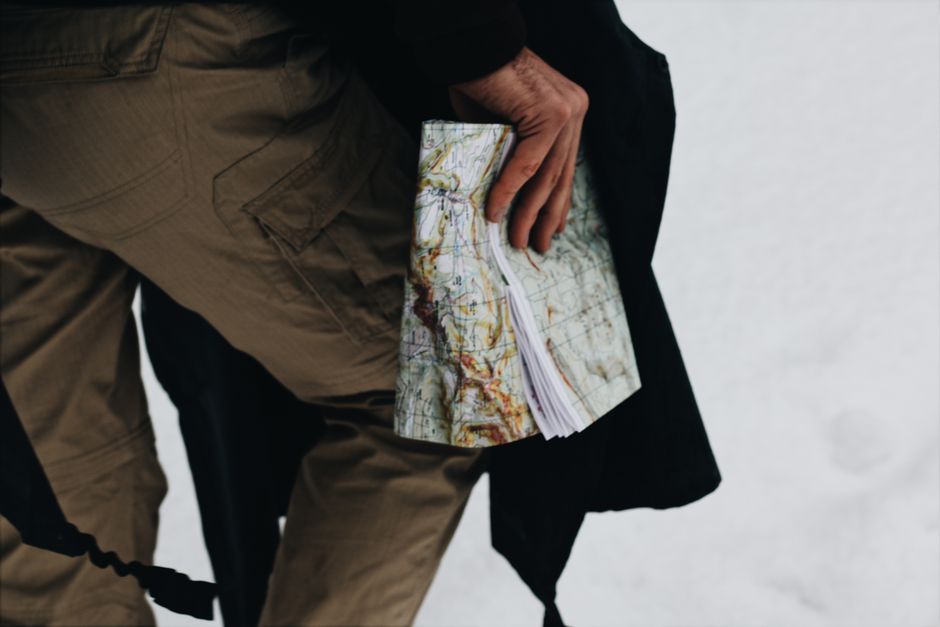 Close-up of a person holding a map against a snowy backdrop, suggesting outdoor exploration.